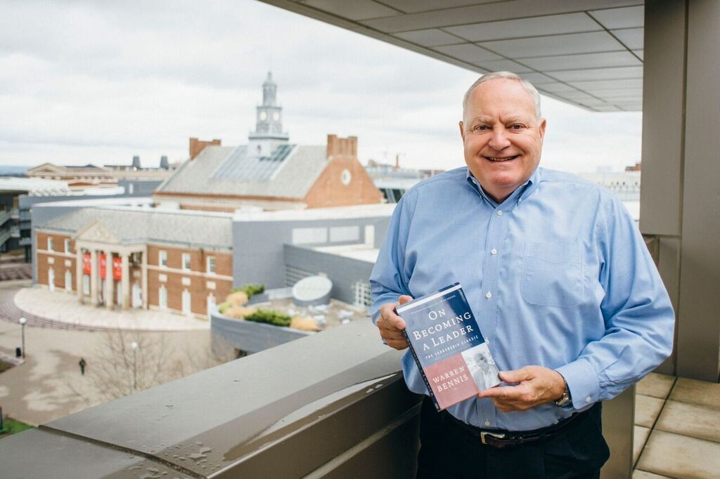 A man in a blue shirt holds a book.