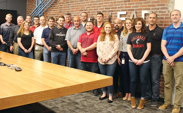 Approximately 20 of Enerfab's UC graduates and co-op students stand in Enerfab's boardroom