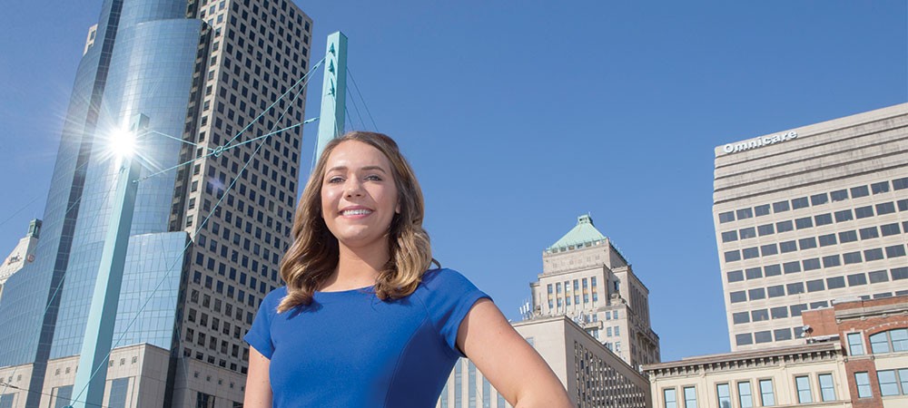 Emily Bleuher standing in downtown Cincinnati with office buildings visible in the background