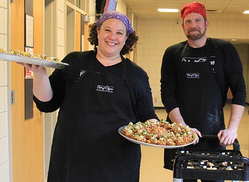 Chef Jaime Carmody, left, and an associate carry dishes of food through Lindner Hall