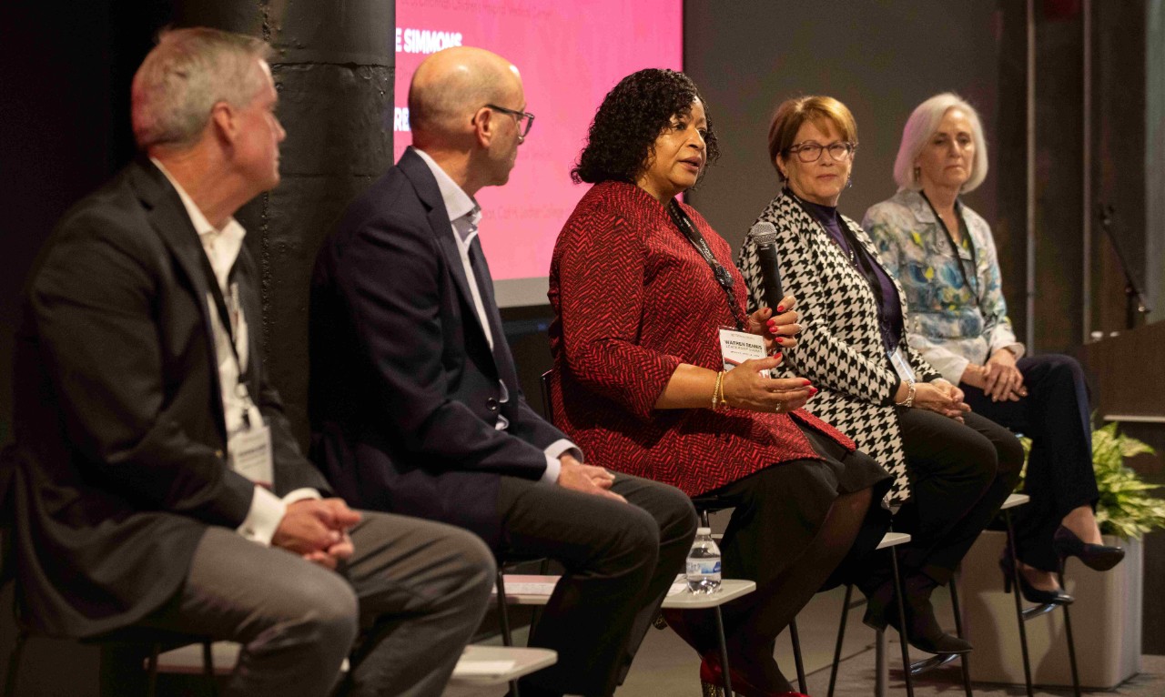 Three women and two men speak on a panel while seated.