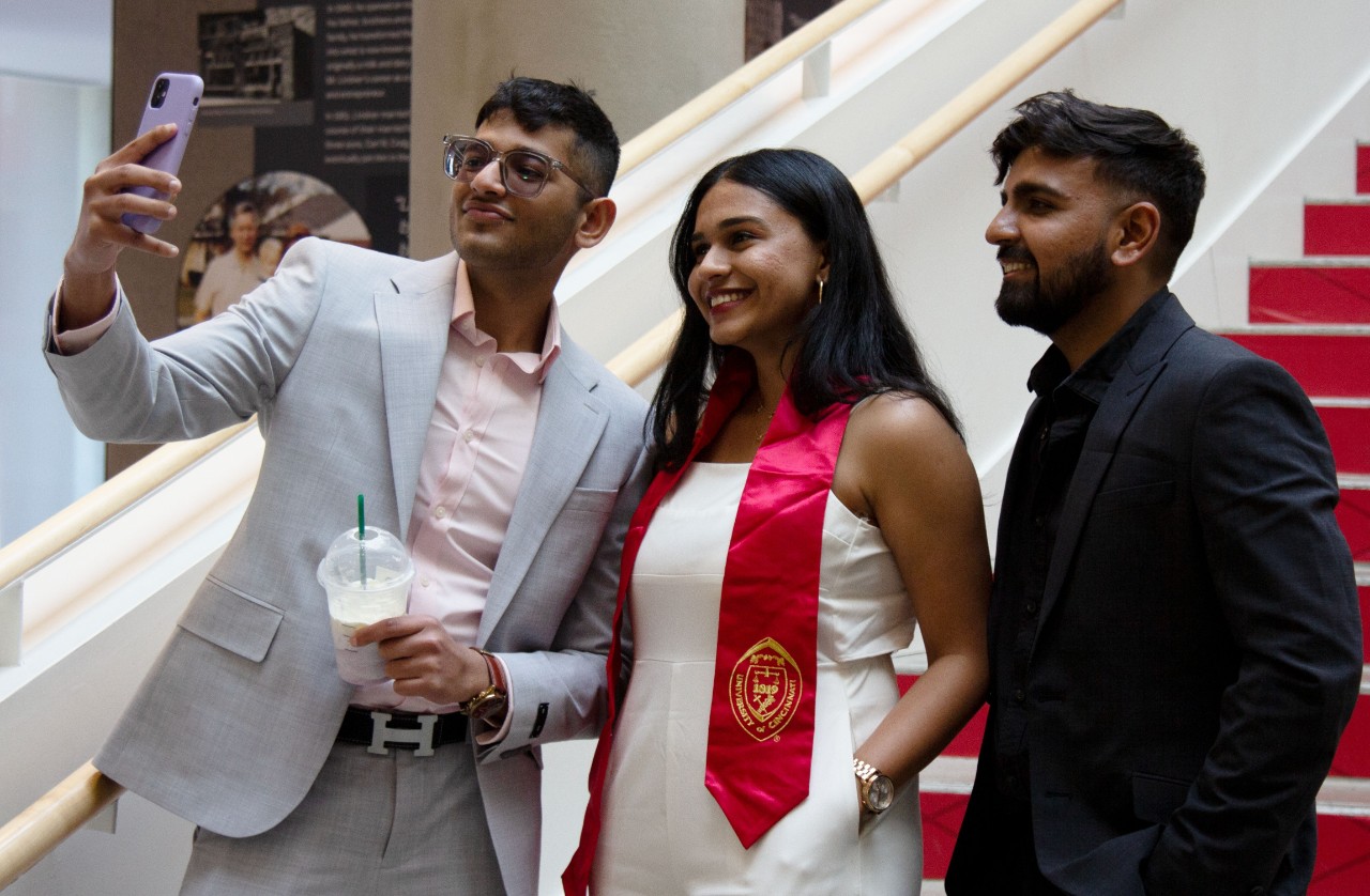 Three students pose for a picture, with one holding a phone for a selfie.