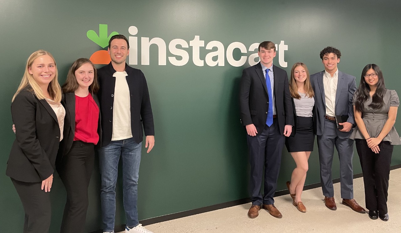 Seven Lindner Business Honors students posed against a green background at the Instacart corporate office