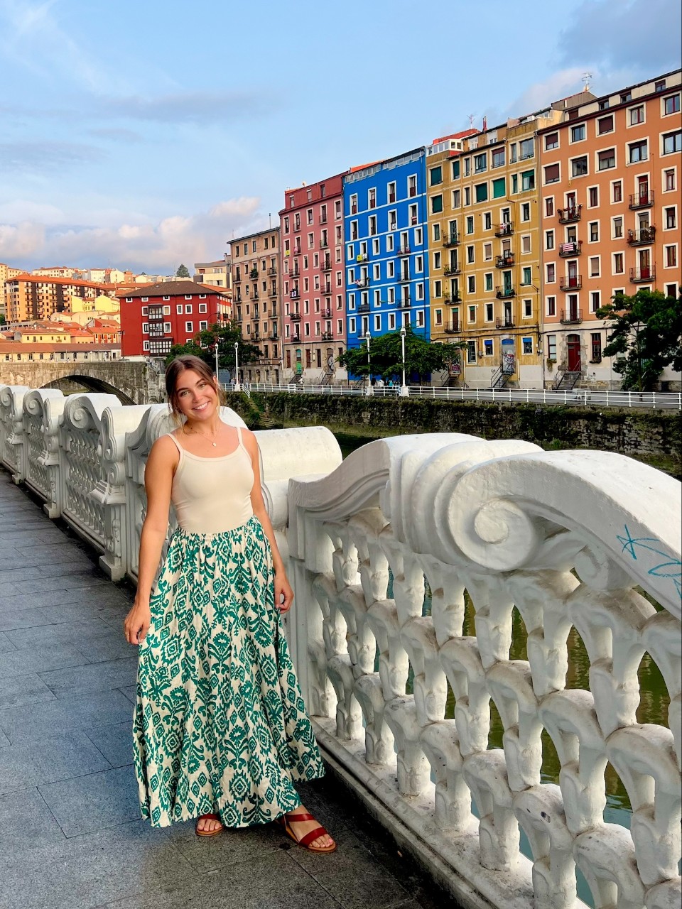 Student in Spain posing in front of bridge and colorful buildings.
